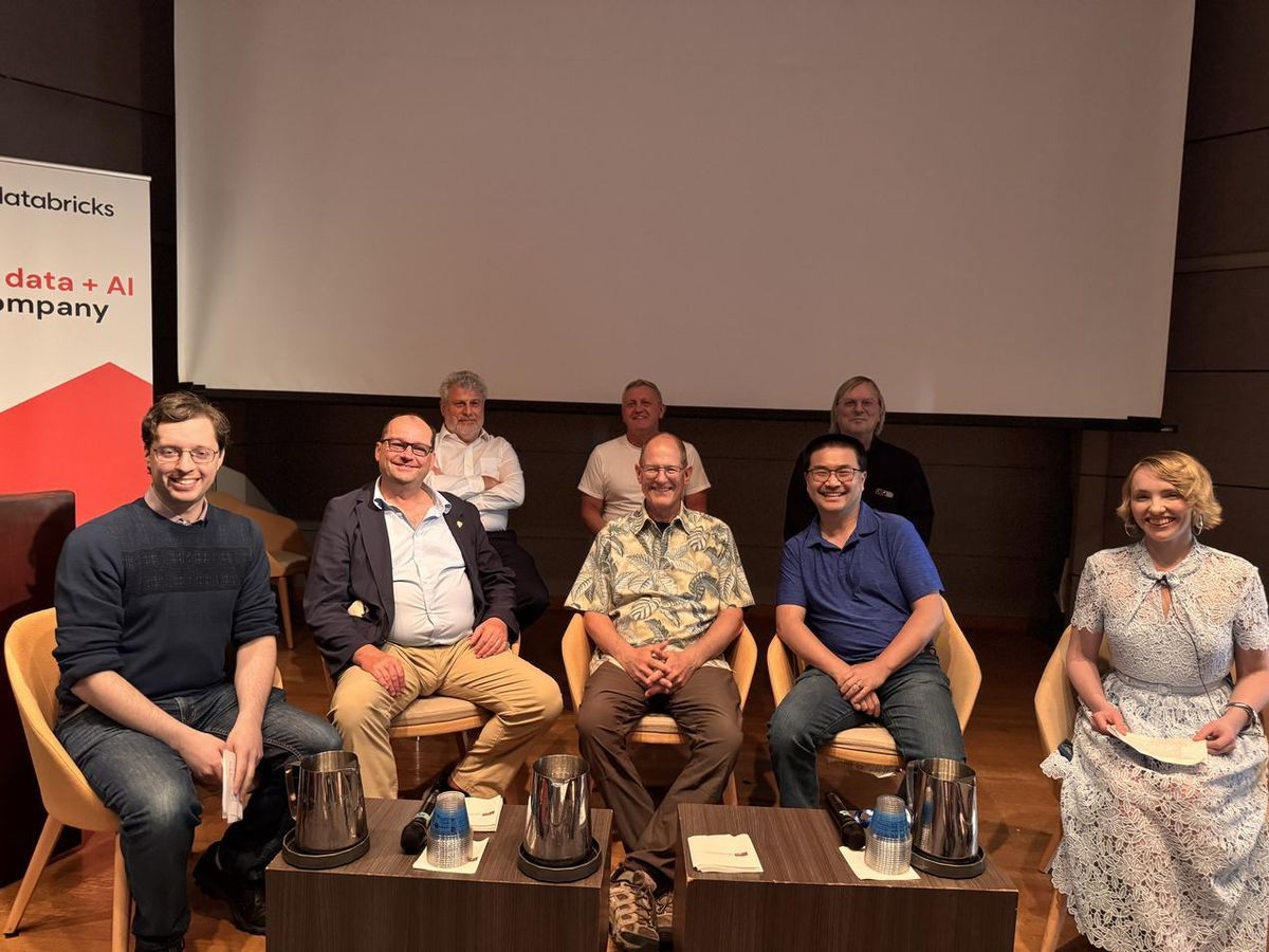 Panelists smiling together on stage after the 30 Years of PostgreSQL retrospective